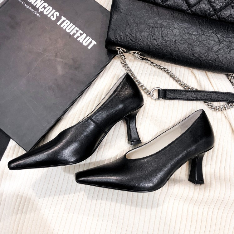 Black high-heeled shoes on a textured surface with a black handbag and book in the background.