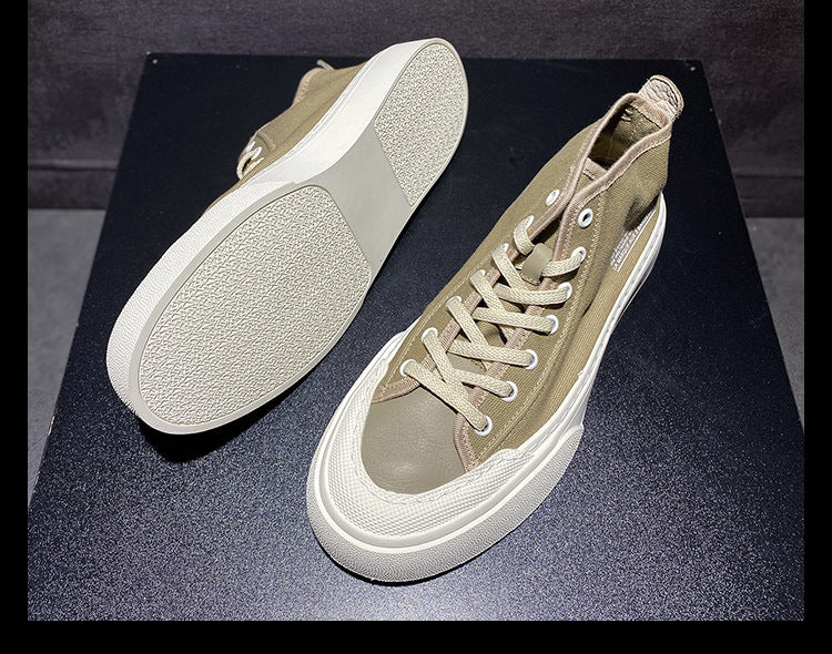 Pair of beige sneakers on a black surface with a dark background