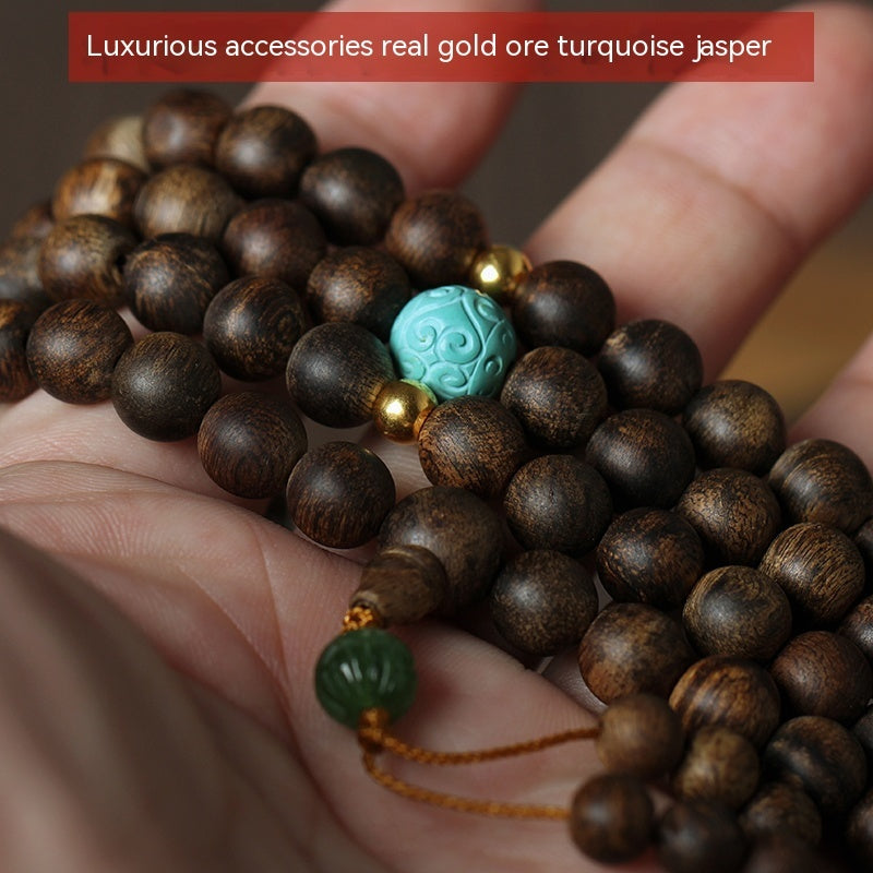 Close-up of a wooden beaded bracelet with turquoise and green beads held in hands.