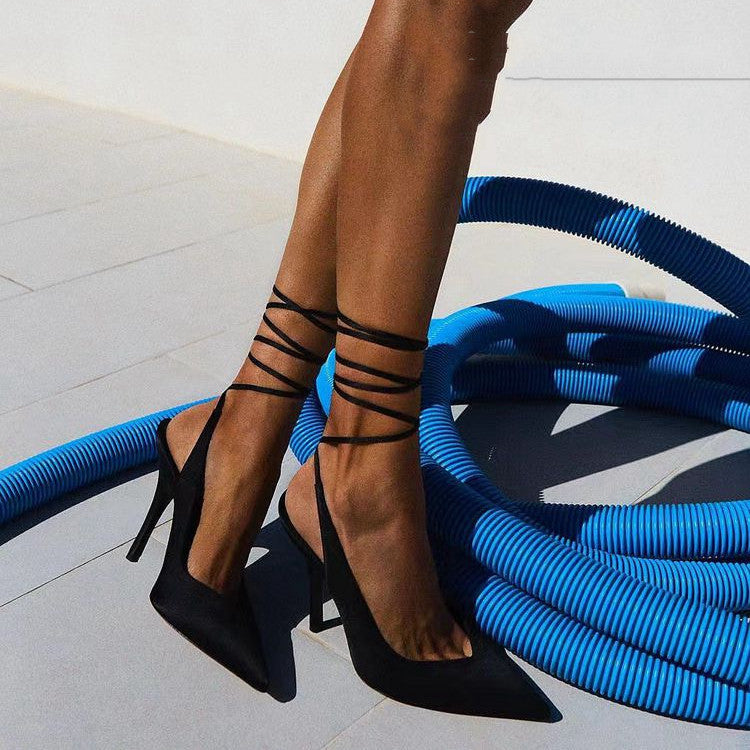 Black high-heeled shoes with strappy design on a light background