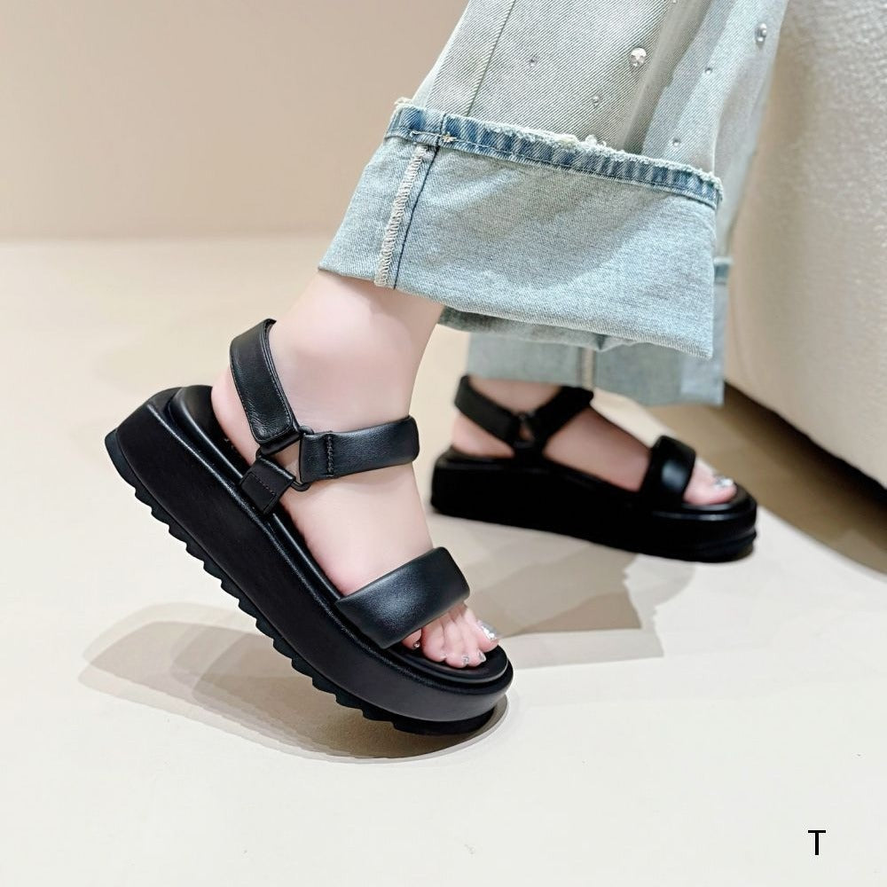 Black sandals worn with light blue jeans on a neutral background