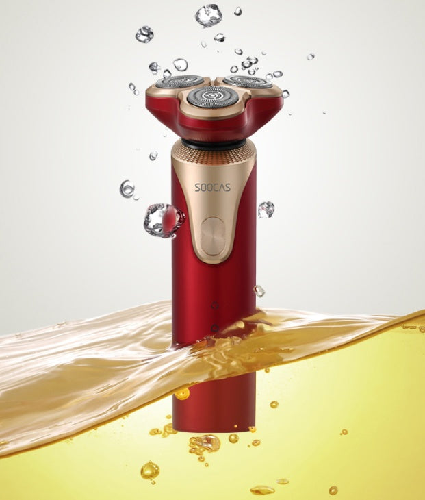 Red electric shaver with water and soap bubbles on a white background