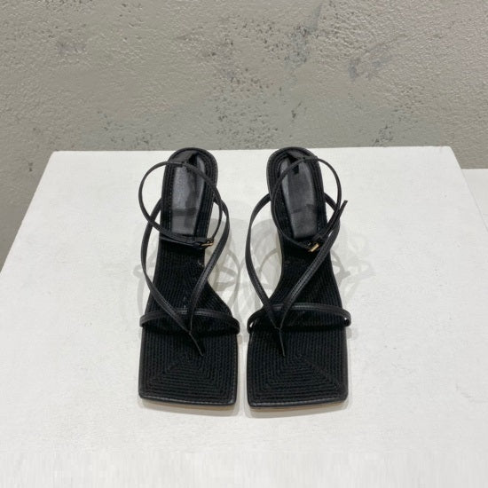 Pair of black high-heeled sandals on a white surface with a gray background