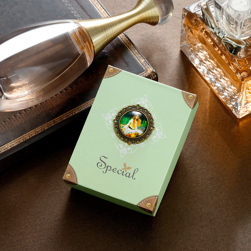 Green gift box with decorative emblem and 'Special' text on a wooden surface with a bottle and perfume bottle.