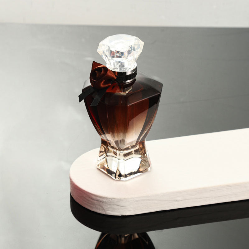 Perfume bottle with a diamond-shaped cap on a white surface