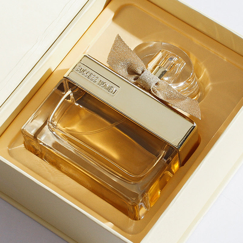 Perfume bottle with gold cap and bow in a decorative box on a white background