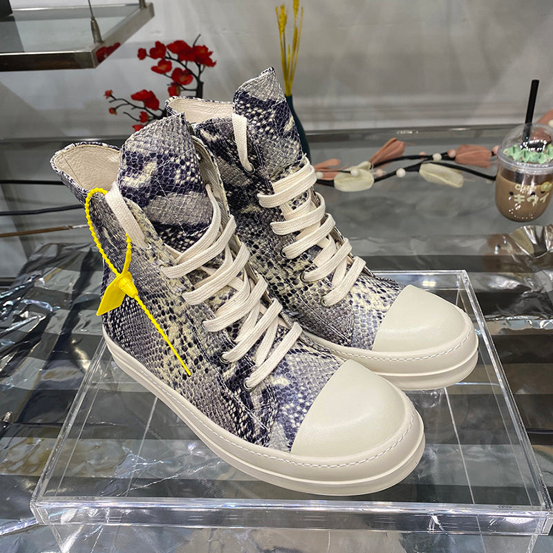 High-top sneakers with snake print and white laces on a clear stand.