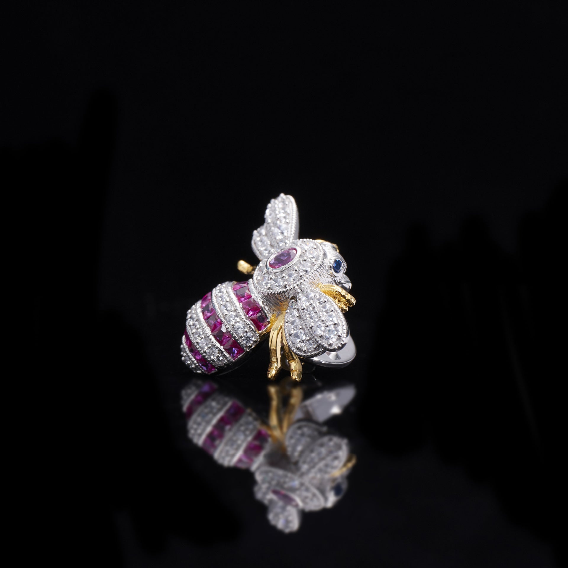 Jewelry item shaped like a bee with gemstones on a black background