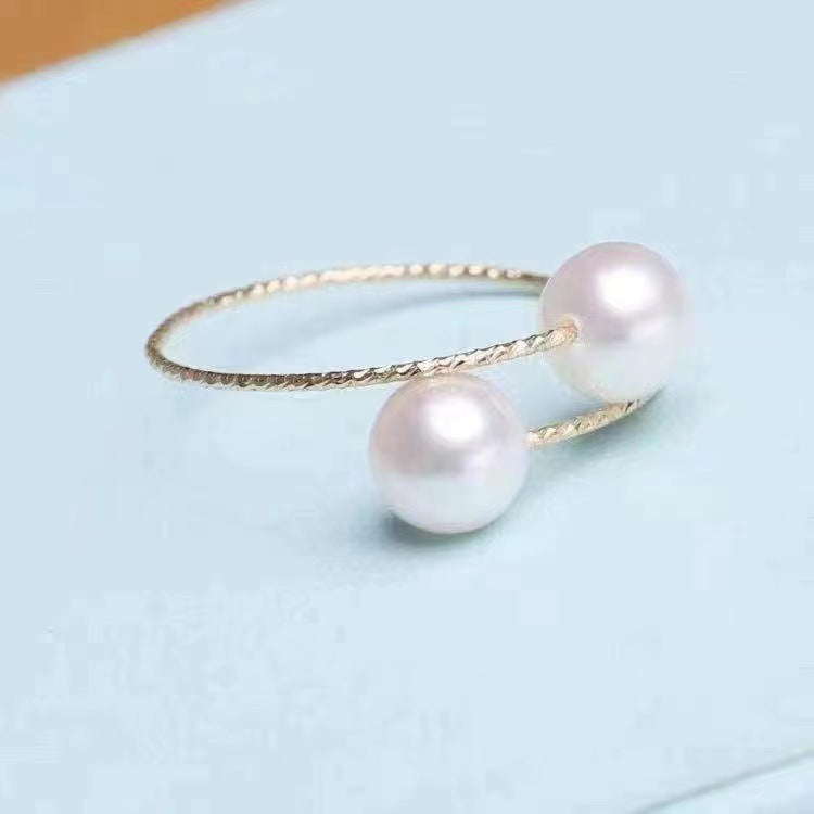 Gold ring with two pearls on a light blue background