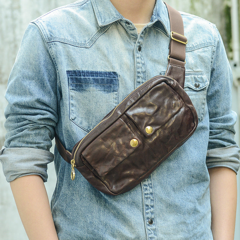 Person wearing a brown leather waist bag over a denim shirt
