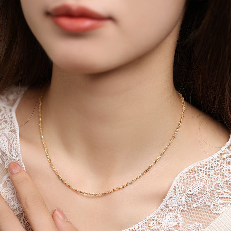 Gold necklace worn by a person with a blurred background