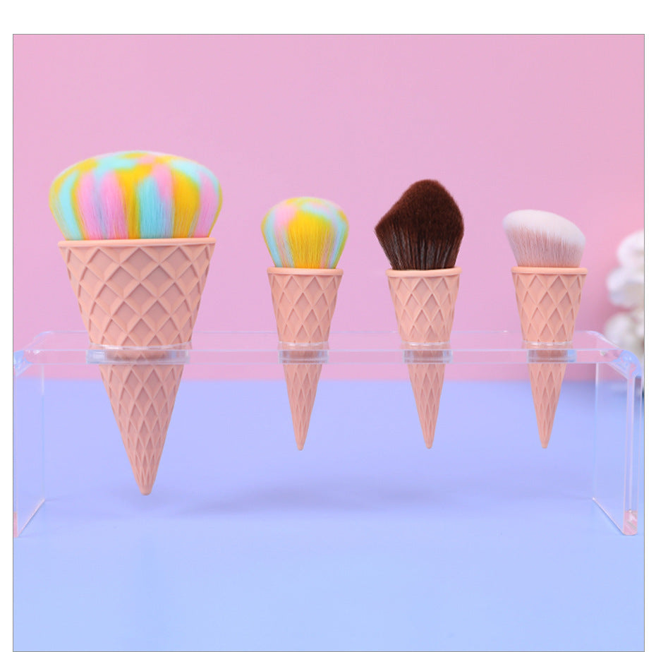 Makeup brushes shaped like ice cream cones with colorful toppings on a pink and blue gradient background.
