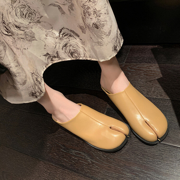 Beige tabi shoes worn with floral pants on a dark wooden floor.