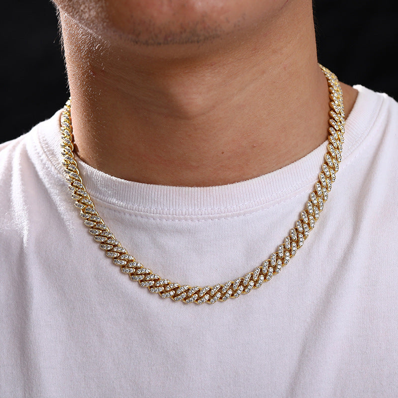Gold chain necklace worn by a person on a white shirt with a black background