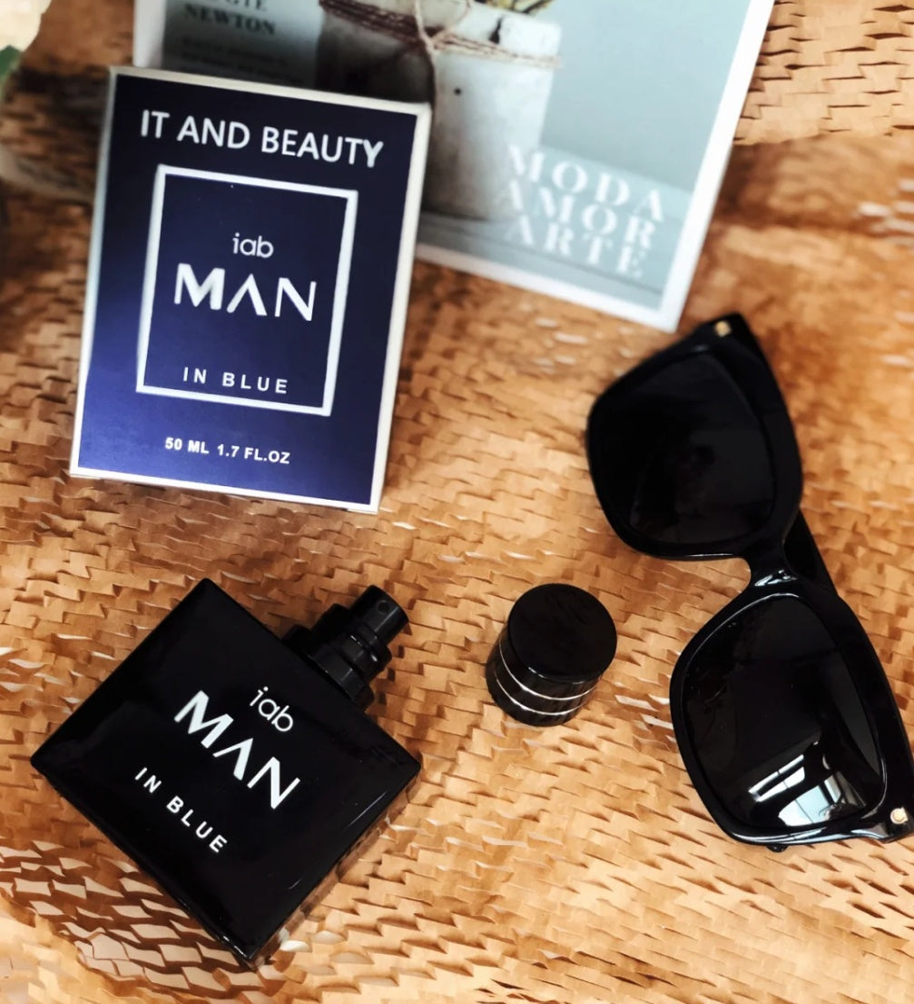 Perfume bottle and packaging labeled 'itab MAN IN BLUE' on a woven surface with sunglasses.