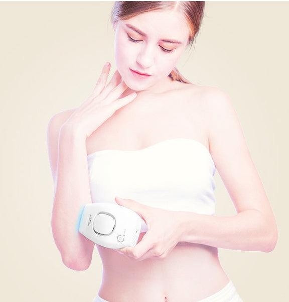 Woman using a hair removal device on her arm with a plain background
