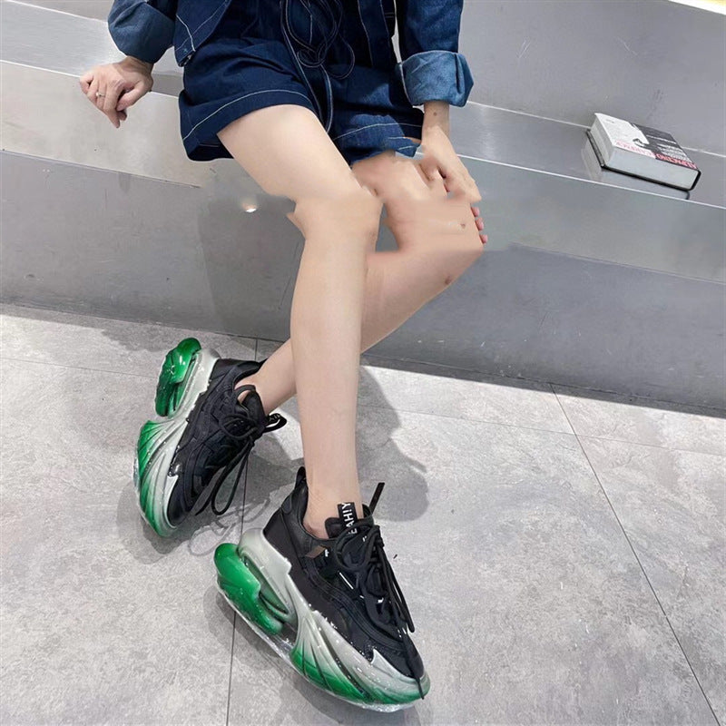 Person wearing black and green sneakers on a gray floor.
