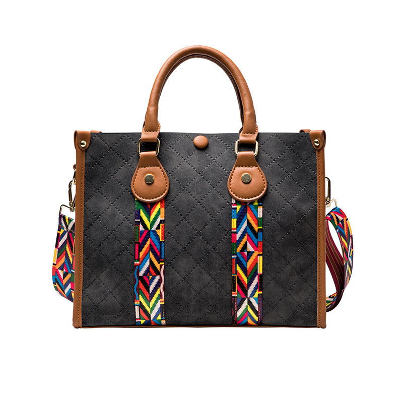 Black quilted handbag with brown handles and colorful strap on a white background