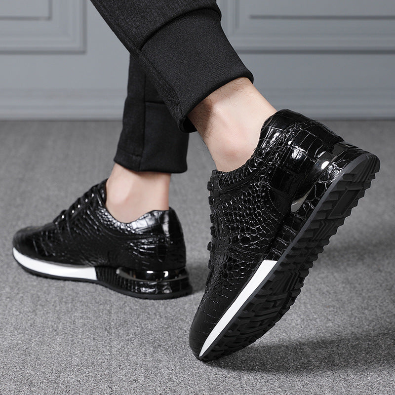 Black shiny shoes worn with black pants on a gray floor.