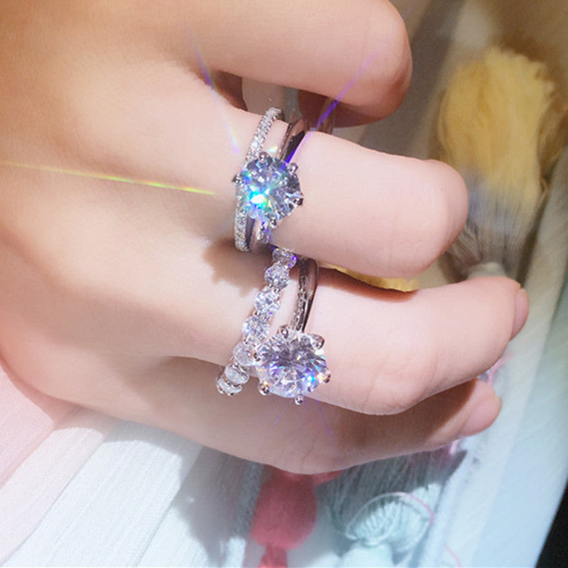 Close-up of a hand wearing two silver rings with gemstones.