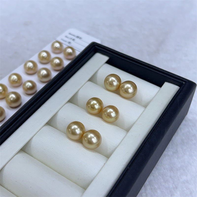Pearl earrings in a jewelry box with additional pearls on a white background