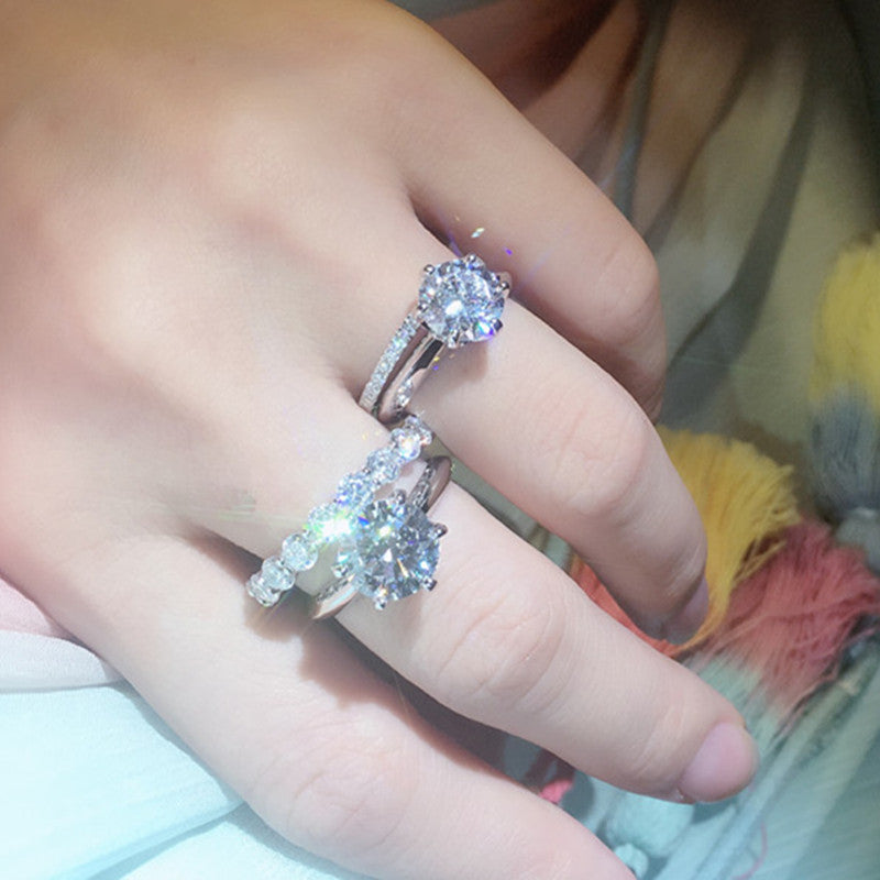 Close-up of a hand wearing two diamond rings with a blurred background