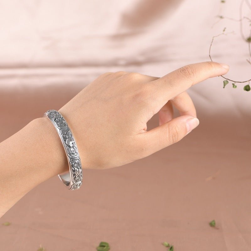 Silver bracelet on a hand against a soft pink background