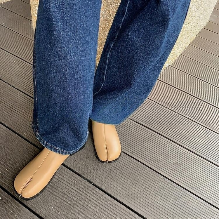 Person wearing blue jeans and beige shoes on a wooden deck