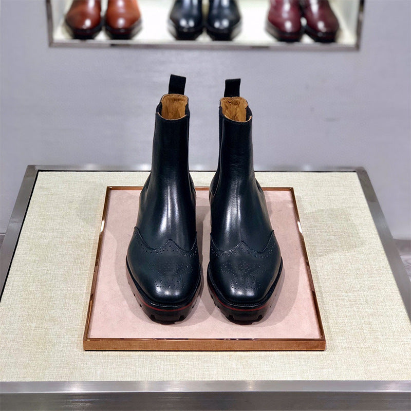 Pair of black leather boots on a pink display mat with shoes in the background.