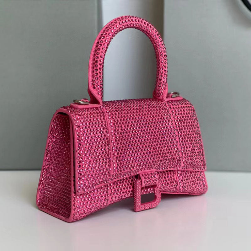 Pink woven handbag on a reflective surface with a neutral background