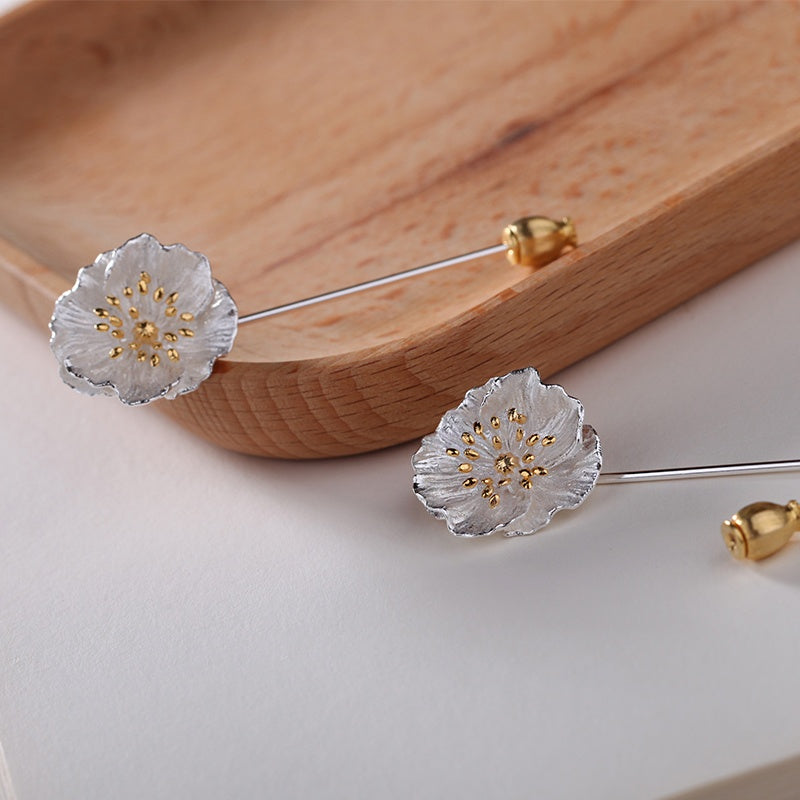 Floral earrings with gold accents on a wooden and white surface