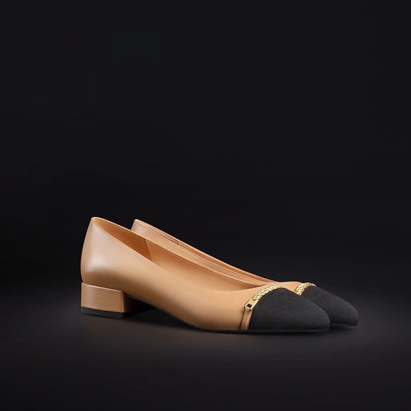 Pair of beige and black shoes with gold accents on a black background