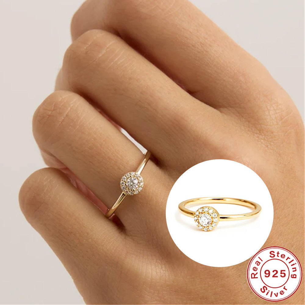 Gold ring with a diamond on a hand, featuring a 'Real Sterling Silver 925' stamp.