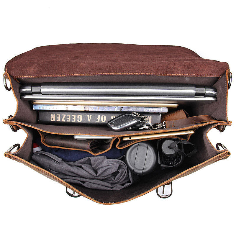 Brown leather bag with compartments containing a laptop, books, keys, and other items on a white background.