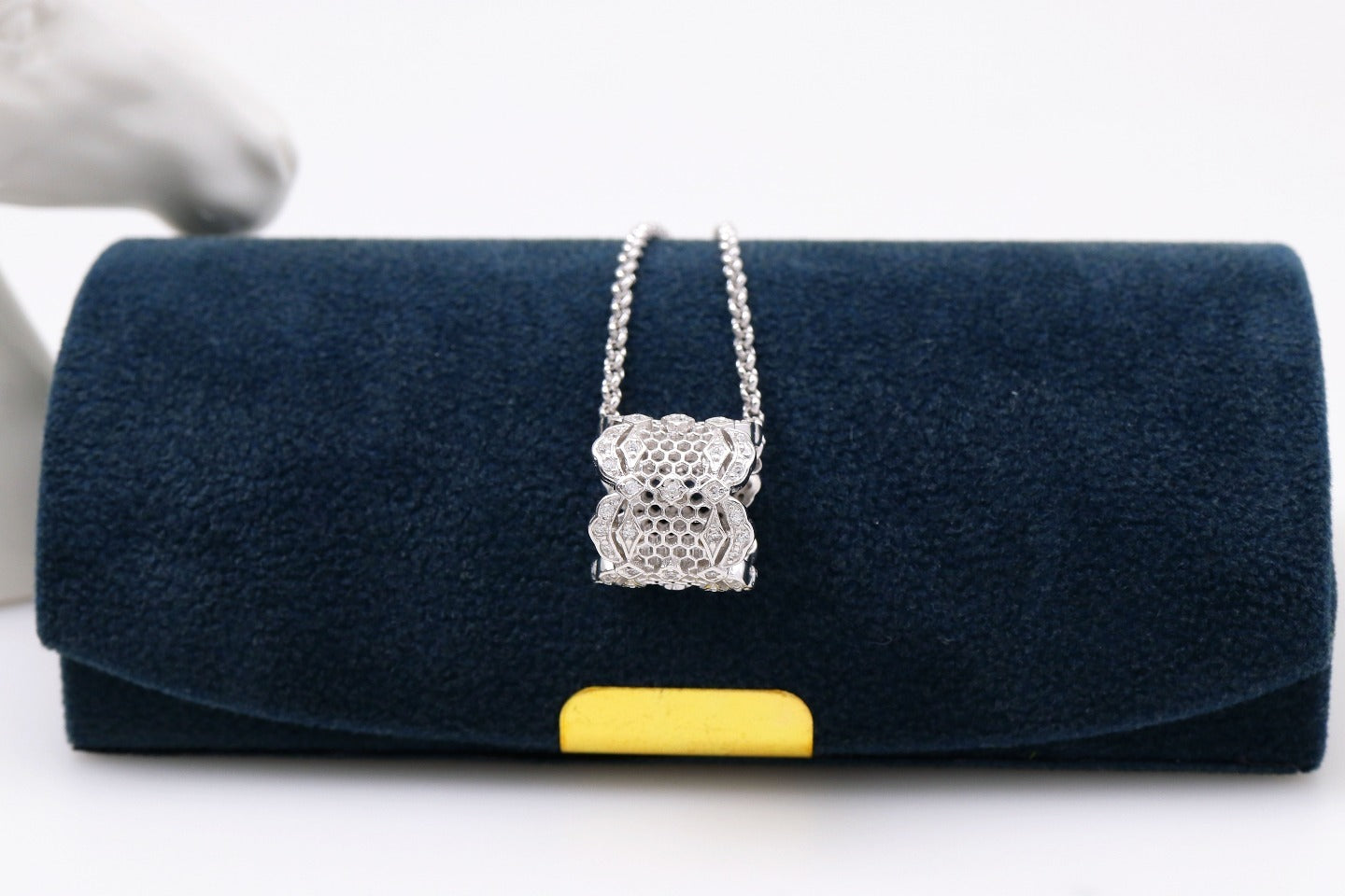 Navy blue clutch bag with a yellow accent and silver chain detail on a white background