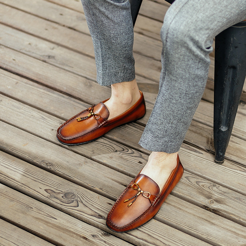 Brown loafers worn with gray pants on a wooden floor