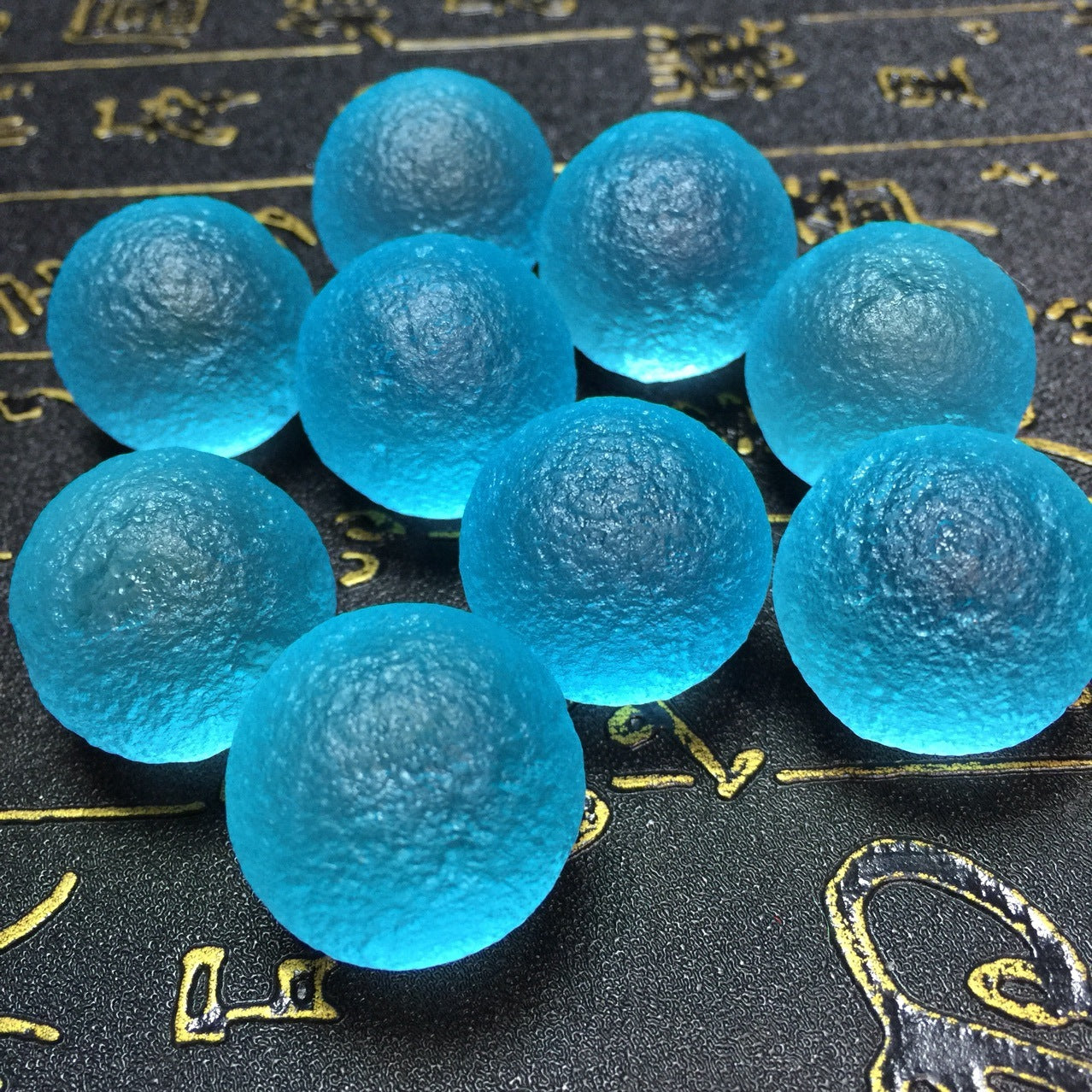 Blue gel beads on a dark surface with gold text