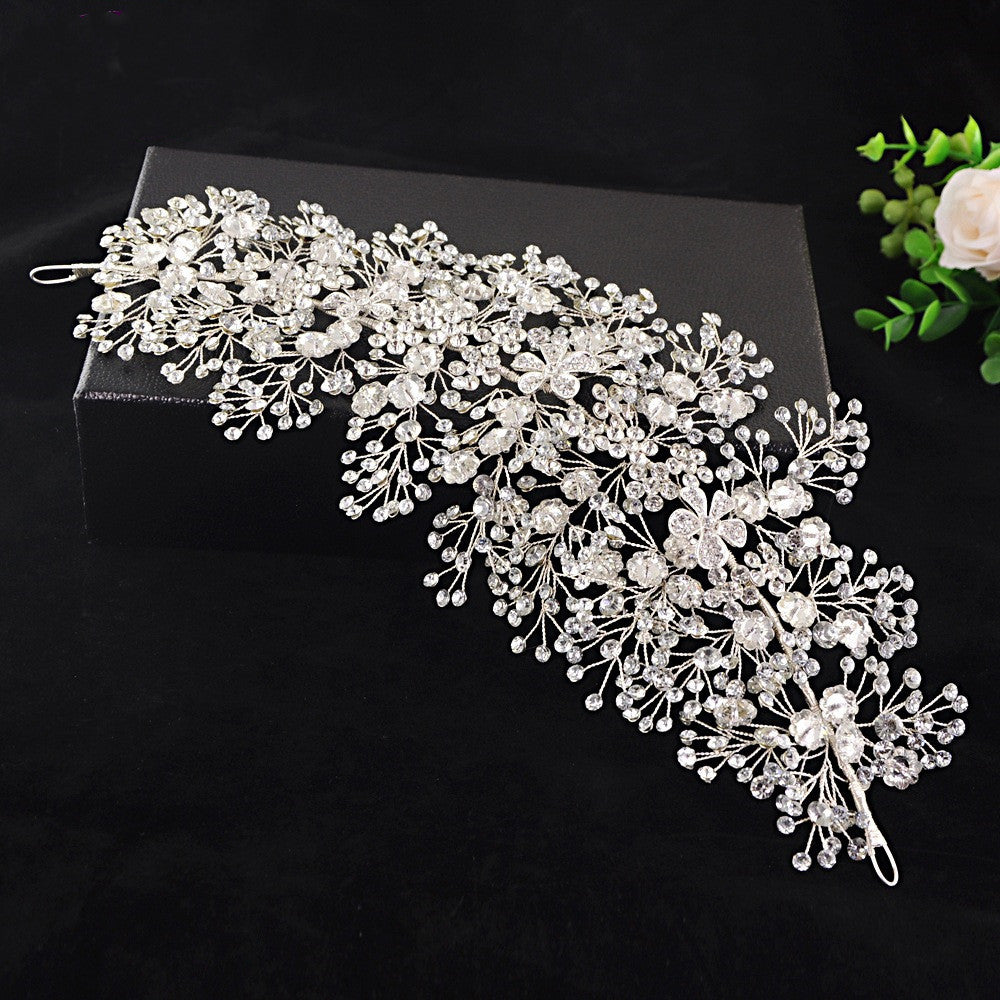 Silver floral hair accessory on a black box with greenery in the corner
