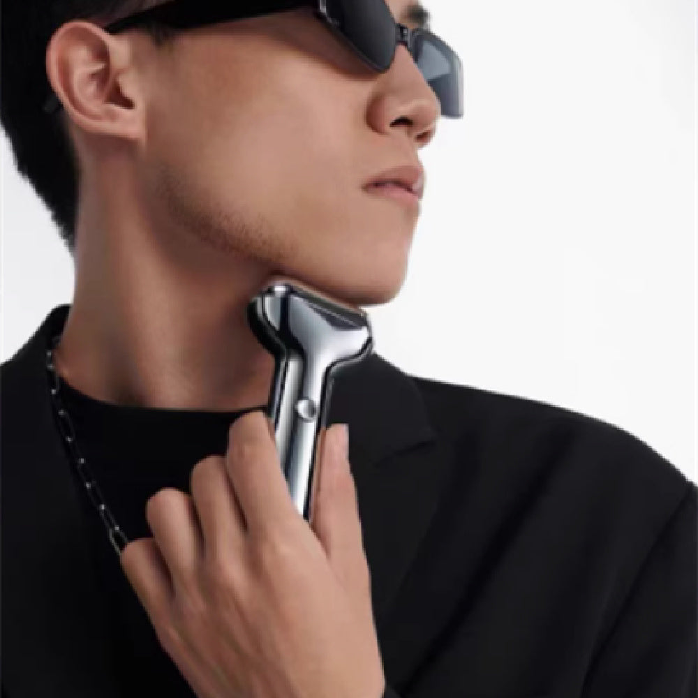 Person using a grooming tool on their neck with a neutral background