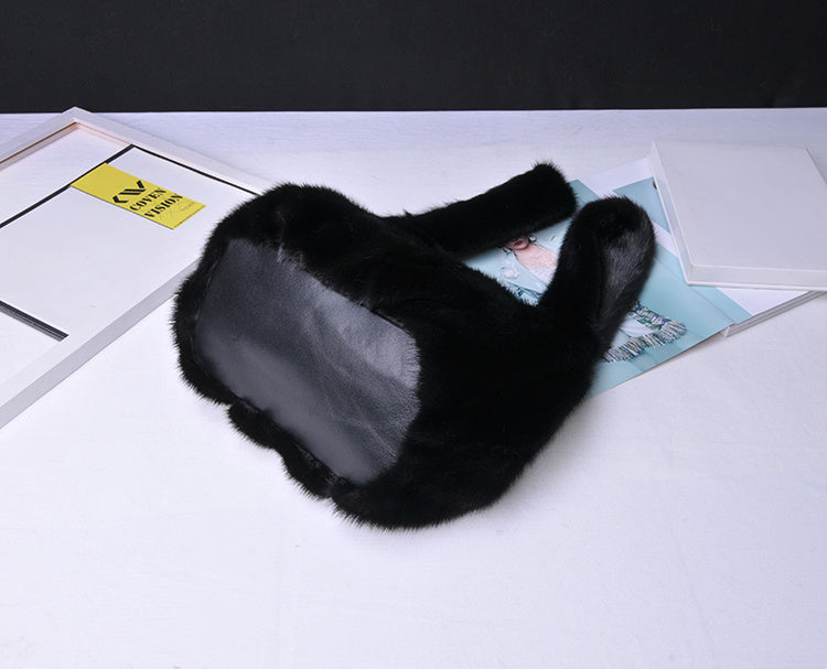 Black fur ear muffs on a white surface with a blurred background