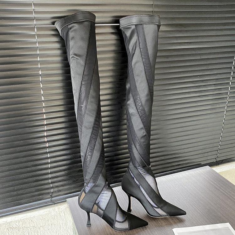Gray over-the-knee boots on a stand against a neutral background