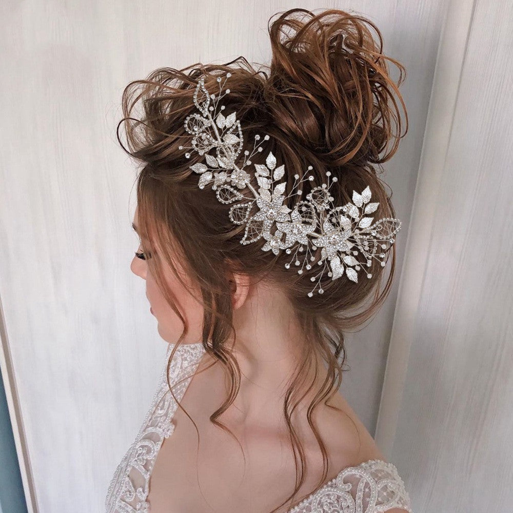 Woman with an elegant updo hairstyle featuring a decorative headpiece against a neutral background