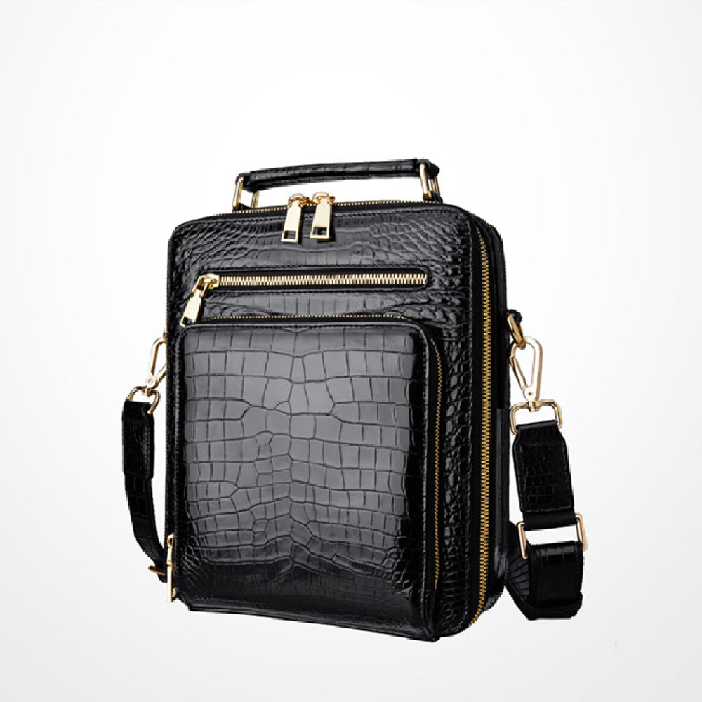 Black crocodile-patterned handbag with gold accents on a white background