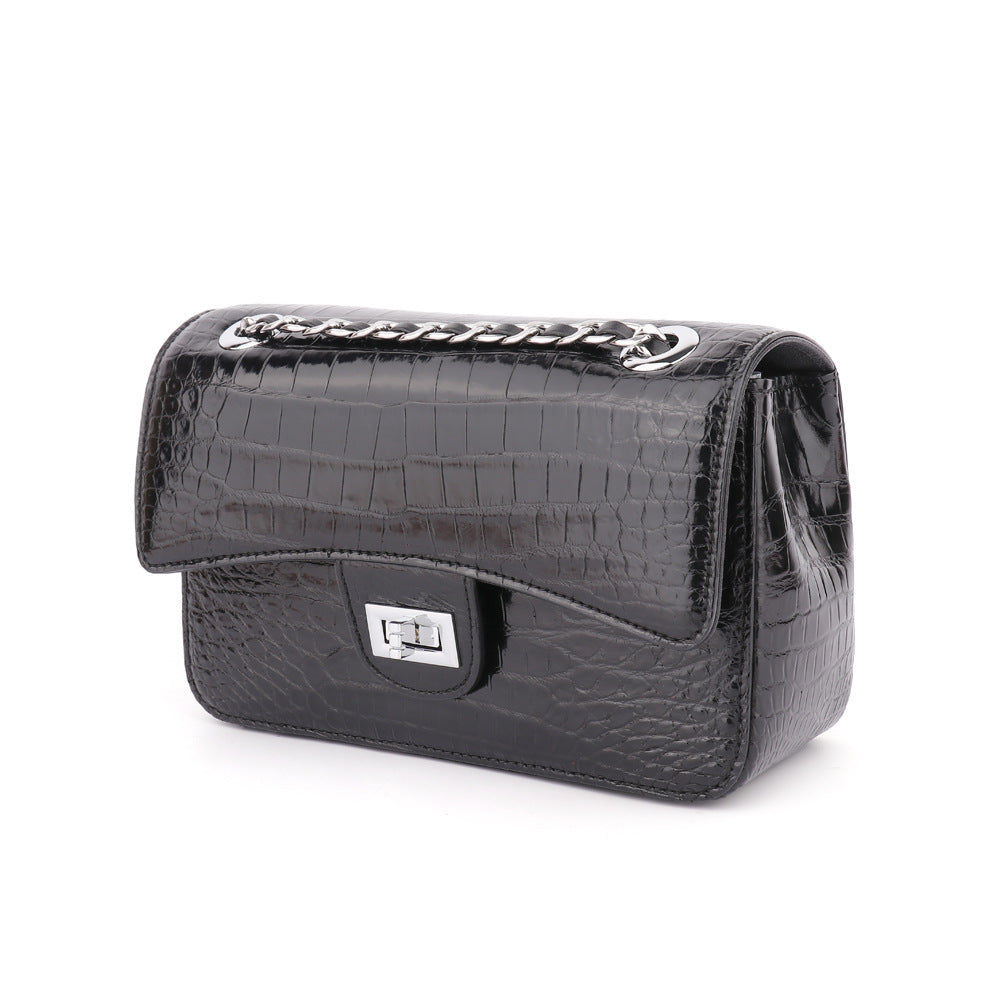 Black crocodile-patterned handbag on a white background