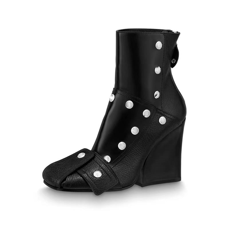 Black wedge heel boot with silver buttons on a white background
