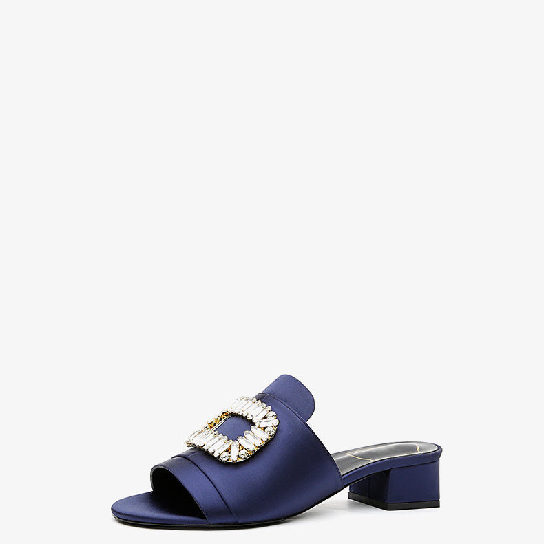 Blue sandal with a decorative buckle on a white background