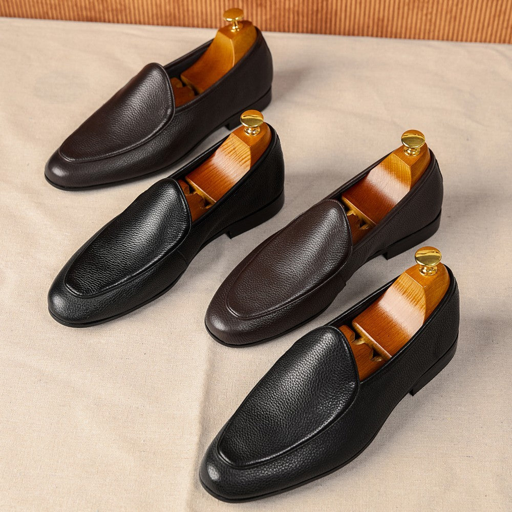Four black leather loafers with wooden insoles on a beige surface