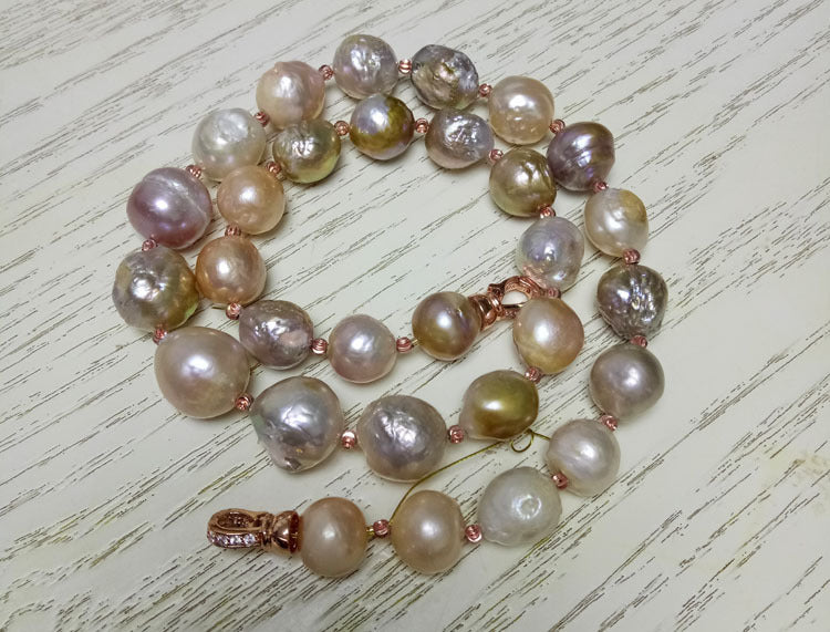 Pearl necklace with copper accents on a light wooden surface