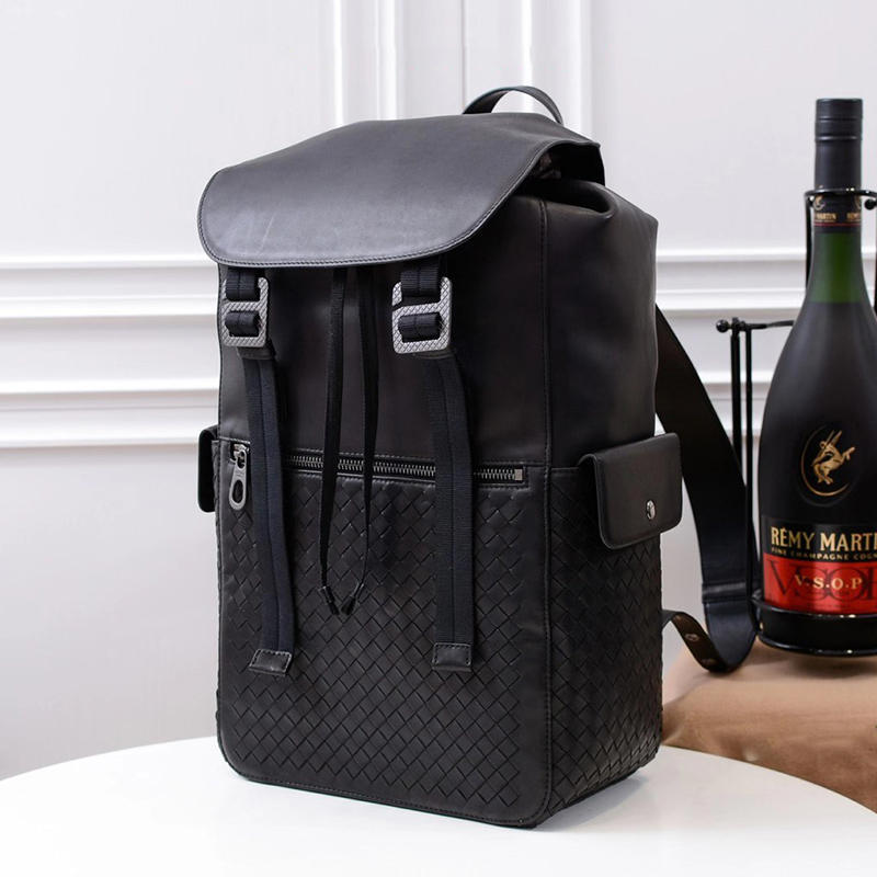 Black backpack with a bottle of Remy Martin VSOP cognac on a white surface.