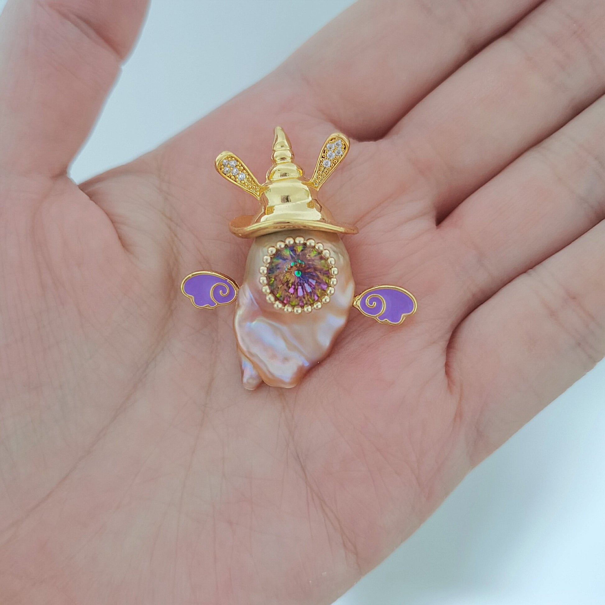 Gold and purple decorative item on a hand with a white background